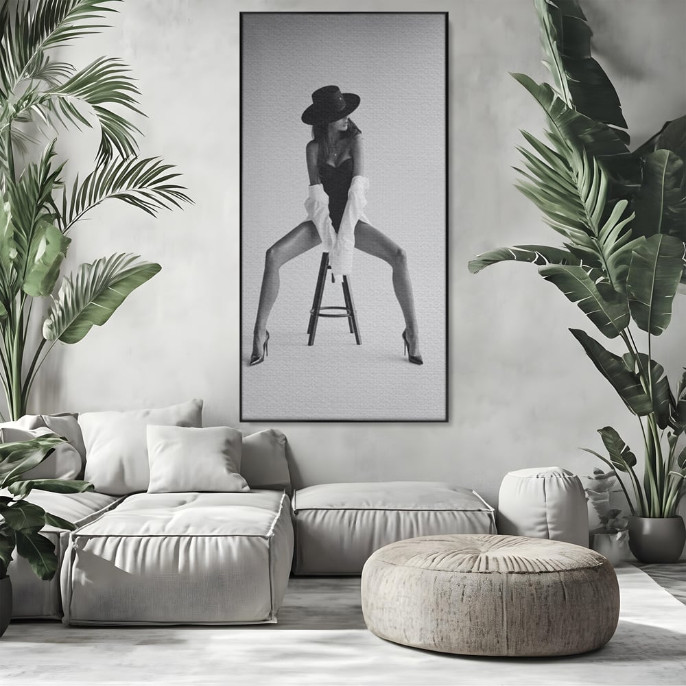 Tablou canvas cu tablou canvas cu femeie pe scaun, in rama de aluminiu negru, pe perete intr-un living